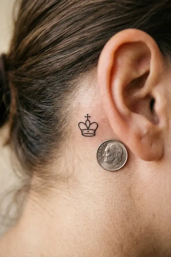 Größenvergleich: winziges Mikro-Tattoo hinter dem Ohr neben einer Münze